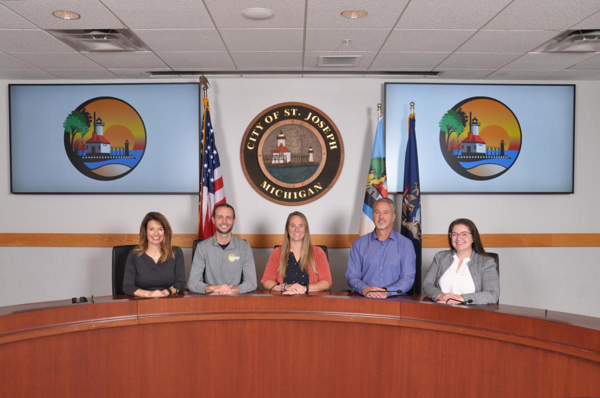 City commissioners sit around the commission table in front of the City's seal
